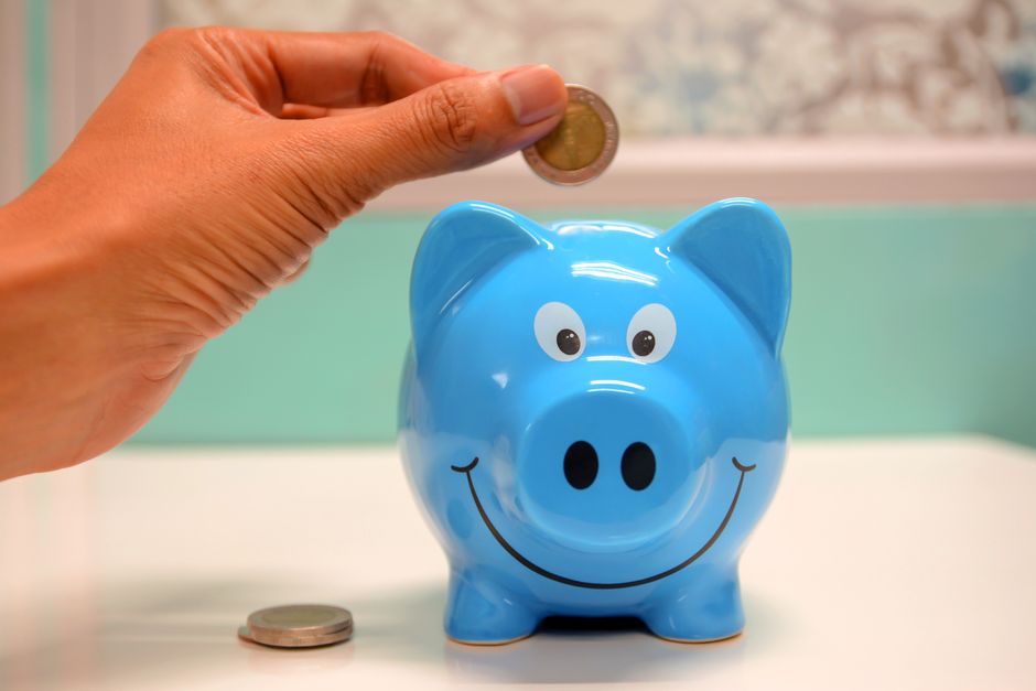 青い貯金箱に硬貨を入れる手元