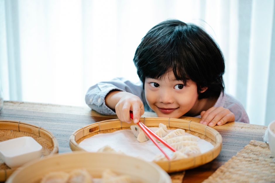 箸で餃子をつまもうとする男の子